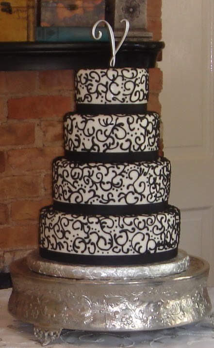 Four tier white fondant wedding cake with black scrolls and ribbons